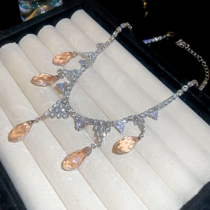 Macro shot of champagne zircon teardrop tassels on silver chain in soft jewelry box