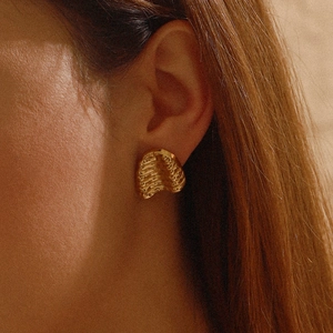 Modern 18K gold-plated stainless steel earrings with hammered texture worn by a model