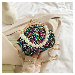 Detail of colorful sequin shell bag featuring pearl handle and golden chain strap