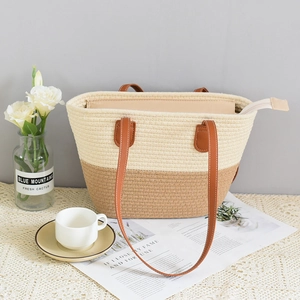 Detail of two-tone woven tote bag featuring brown leather straps and zip closure