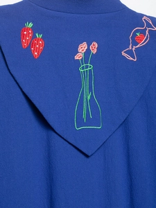 Detail shot of strawberry and candy embroidery on navy blue textured fabric hoodie