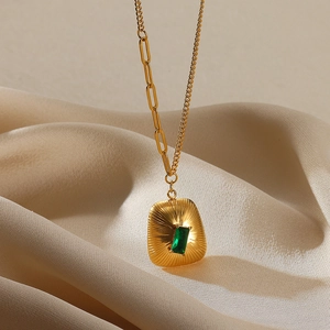 Detail of 18K gold necklace with green zircon pendant on champagne silk fabric