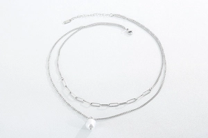 Detailed close-up of double layer silver chain necklace with pearl pendant and paperclip link