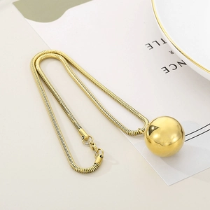 Detailed view of polished gold sphere pendant on a delicate snake chain necklace