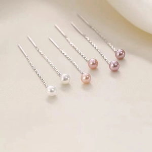 Dettaglio di lunghe nappe d'argento con perle bianche rosa e viola su sfondo di stoffa
