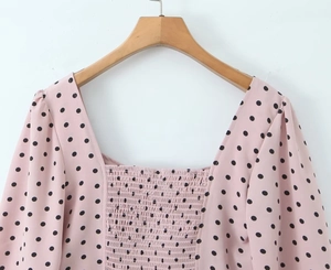 Détails du col carré et du bustier smocké élastique sur le haut rose à pois noirs