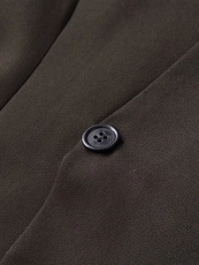 Macro shot of dark olive fabric texture and a black four-hole button on the blazer