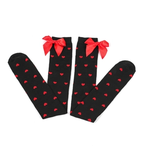 Detail of black thigh high stockings with red heart pattern and knitted red bows
