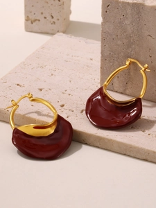Close-up of red enamel wave charms on gold plated stainless steel hoops jewelry