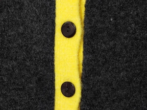 Close-up of contrast color knitwear with yellow placket and black circular buttons
