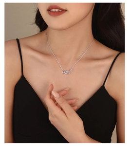Close-up of heart and infinity silver necklace with zircon on a model wearing black