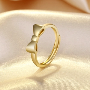 Macro detail of golden matte bow ring with adjustable open band on champagne silk fabric