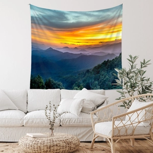Landscape tapestry showing sunset mountain layers above a white sofa in a boho room