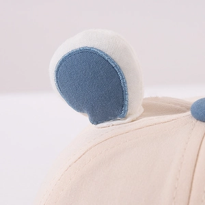 Detailed close-up of cute bear ears and embroidery on this off-white cotton baby baseball cap