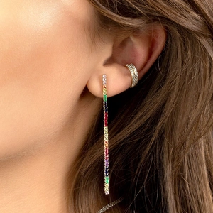 Elegant gold earrings with colorful rainbow zircons and matching cuff shown on model