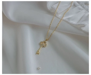 Macro detail of a gold-plated S925 silver key necklace with sparkling zircon clover head