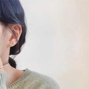 Close-up of minimalist gold heart studs and silver ball earrings for multiple piercings