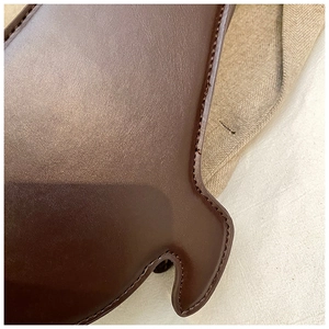 Close-up of deep brown leather bag showing fine stitching and high-quality grain texture