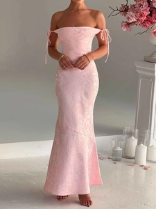 Detail of elegant pink jacquard fishtail dress with tie-shoulder strap and floral backdrop