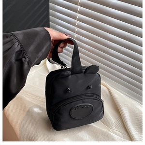 Detail of cute black nylon handbag featuring bear ears design and top carry handle
