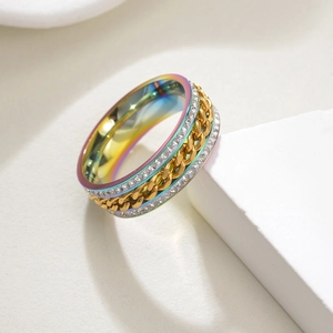 Détail d'une bague arc-en-ciel rotative avec deux rangées de diamants et chaîne dorée sur socle