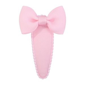 Close-up of pink grosgrain ribbon bow hair clip with wavy scalloped edge detail