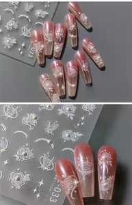 Macro detail of 5D white embossed floral nail stickers with pearls on pink press-on nails