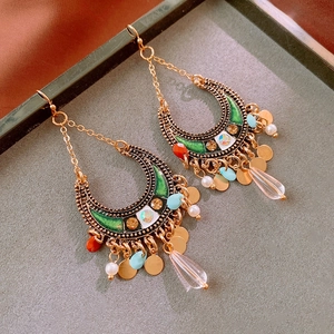Detailed shot of ethnic moon tassel earrings with colorful beads on a grey background