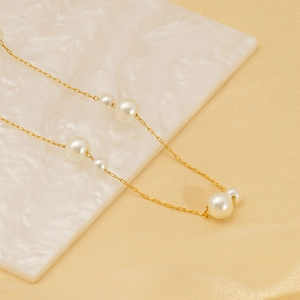 Détail du collier ajustable en titane doré avec d'élégantes paires de perles blanches