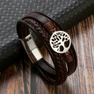 Macro detail of brown braided leather bracelet with silver tree of life charm and magnetic clasp