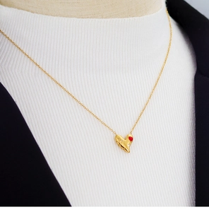 Détail du collier cœur en or 18K avec émail rouge et diamants sur le cou d'un modèle