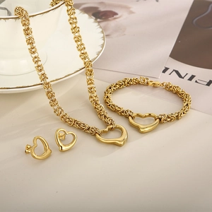 Detailed view of gold heart necklace, bracelet and earrings set on an elegant tabletop