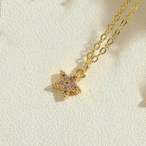 Macro shot of gold star pendant with pink pavé zircons on a textured surface