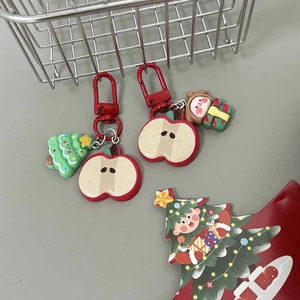 Close-up of festive Christmas apple keychains with cartoon charms on a metal basket
