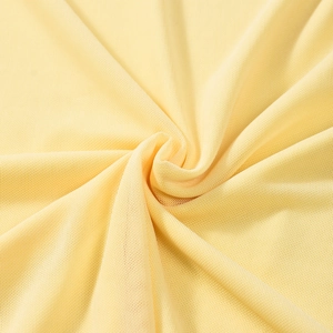Dettaglio macro del tessuto a maglia fine gialla con eleganti pieghe drappeggiate