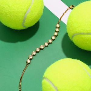 Gold stainless steel tennis bracelet with clear zircon stones on a creative green background