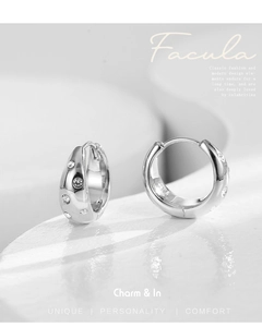 Macro shot of silver circular earrings with pave-set Czech crystals on a stone surface