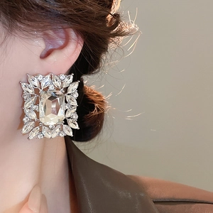 Close-up of silver square earrings with large crystal and sparkling leaf-shaped rhinestones