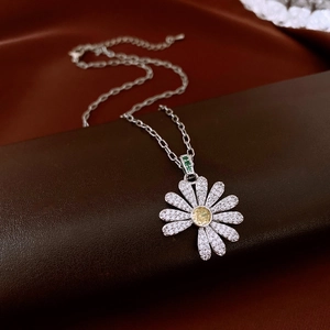 Macro shot of silver daisy pendant with white zircons and yellow gemstone on silk