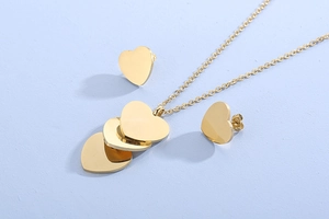 Détail d'un ensemble de bijoux cœur doré avec collier multicouche et boucles d'oreilles