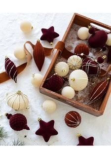 Detail of velvet Christmas ornaments with gold glitter on a rustic wooden tray