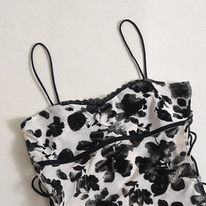 Détail de caraco en maille blanche avec imprimé floral noir, dentelle et laçage latéral