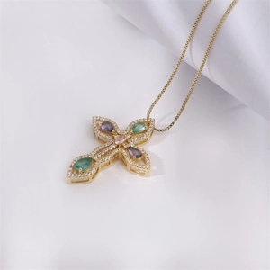 Golden cross necklace with colorful zircons on white background and paper roll