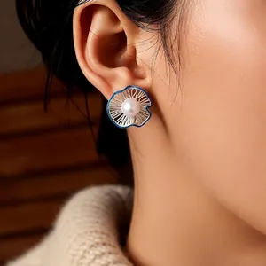 Elegant pearl flower stud earrings with blue mesh petals worn by a model in soft light