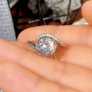 Detalle de un anillo de bodas plateado con circonita grande y engaste en espiral
