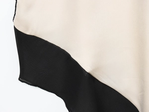Detail aus cremefarbenem Satinstoff mit schwarzem, halbtransparentem Netzgewebe