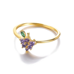 Detail of gold ring featuring a purple grape bunch design with green leaf gemstone