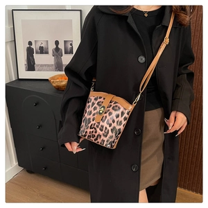 Fashionable leopard print bucket bag with brown strap shown on model in stylish interior