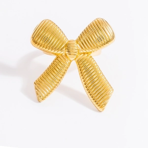 Detailed close-up of golden bow ring with fine horizontal textures on polished surface