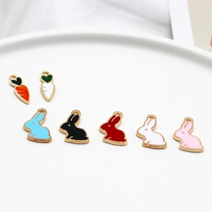 Enamel carrot and bunny alloy charms for jewelry making displayed on a white plate